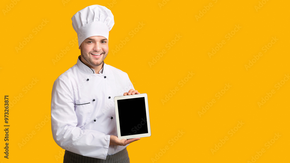 Professional Cook Guy Showing Empty Tablet Screen Standing In Studio Over Yellow Background. Panorama, Mockup Professional Cook Guy Showing Empty Tablet Screen Standing In Studio Over Yellow Background. Panorama, Mockup
