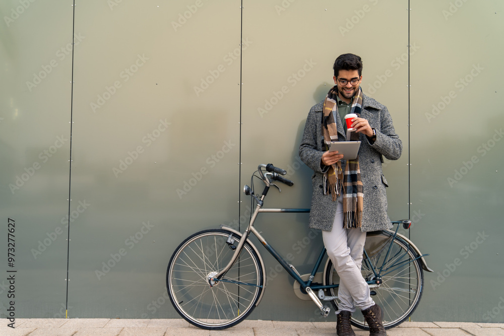 © Dorde - Smiling Young Businessman with Bike and Tablet on Coffee Break