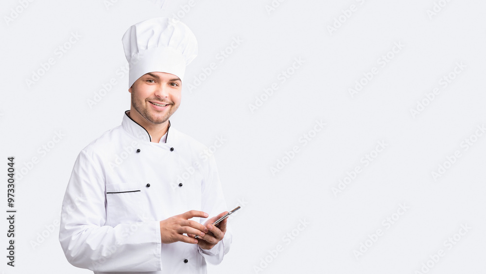Culinary App. Smiling Chef Man Using Smartphone Standing Over White Studio Background. Panorama Culinary App. Smiling Chef Man Using Smartphone Standing Over White Studio Background. Panorama