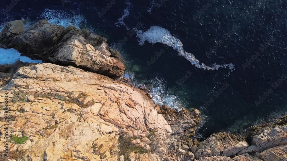 Schwenk nach oben auf einen Felsen an der Küste bei Sonnenaufgang mit Blick auf das Meer