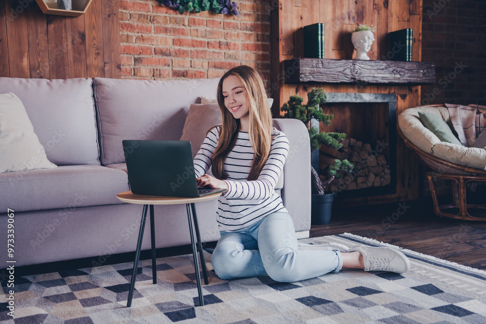 Obraz premium Full body photo of lovely teen lady sit floor netbook relax dressed striped garment spend pastime spacious house indoors room