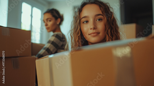 Two young women prepare to move homes, packing their belongings into cardboard boxes