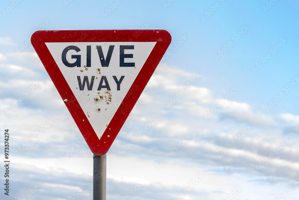 Give way warning red triangle sign with shotgun pellet holes Give way warning red triangle sign with shotgun pellet holes