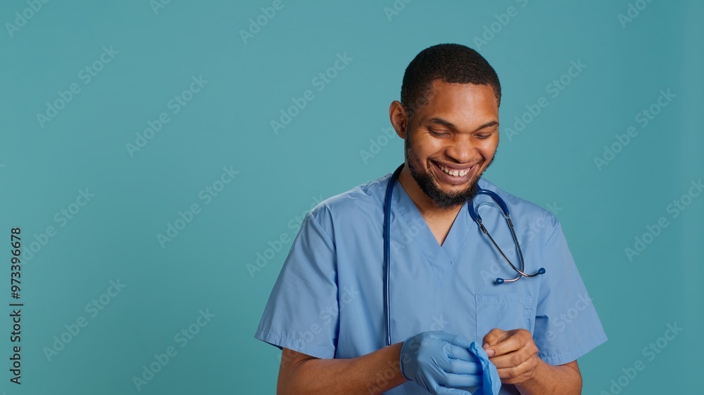 Male nurse putting on rubber gloves, preparing for surgery, isolated over studio background. Practitioner wearing sterile surgical equipment before medical exam, camera A Male nurse putting on rubber gloves, preparing for surgery, isolated over studio background. Practitioner wearing sterile surgical equipment before medical exam, camera A