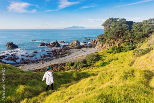 Woman walking on a hiking trail down to a beach in Tawharanui, Warkworth, Auckland, New Zealand. photo