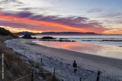 Womanb looking over the beach at sunset at Tawharanui, Warkworth, Auckland, New Zealand. photo