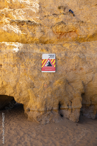 Rockfall warning sign on Algarve's cliffs, Portugal. The sign urges beachgoers to maintain a safe distance from the cliff to prevent potential accidents due to falling rocks photo