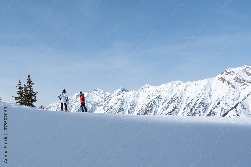 2 skiers on the horizon with snow covered mountains behind, Deer Valley, UT, February 4, 2023 2 skiers on the horizon with snow covered mountains behind, Deer Valley, UT, February 4, 2023
