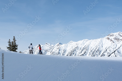 2 skiers on the horizon with snow covered mountains behind, Deer Valley, UT, February 4, 2023