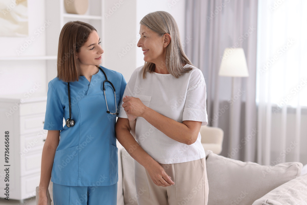 Fototapeta premium Young healthcare worker supporting senior patient indoors. Space for text