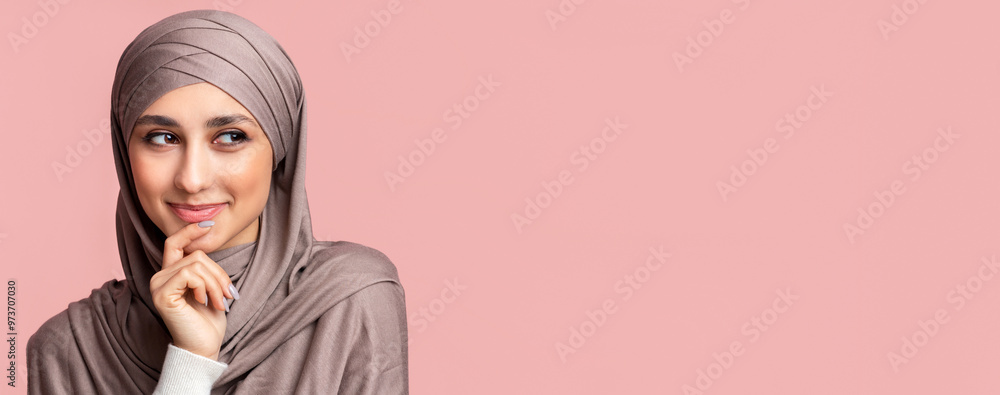 Φωτογραφία Closeup portrait of beautiful smiling muslim woman in hijab smirking, thinking about something and looking aside at copy space on pink background