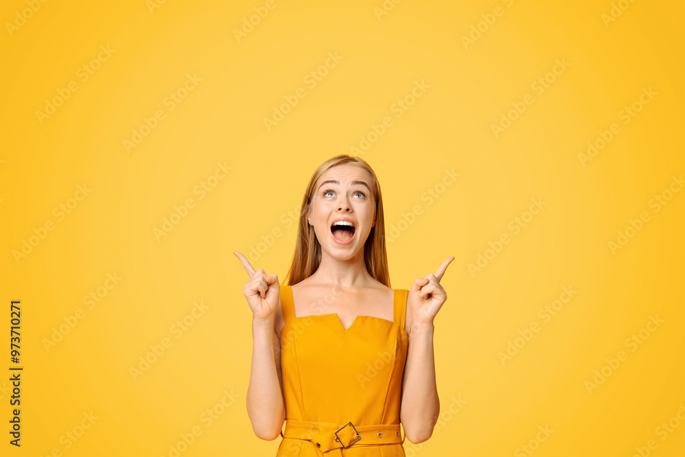 Look There. Excited Young Girl In Summer Dress Pointing Fingers Upwards At Copy Space Above Her Head On Yellow Background Look There. Excited Young Girl In Summer Dress Pointing Fingers Upwards At Copy Space Above Her Head On Yellow Background