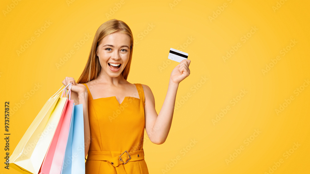 Sales And Discounts. Portrait Of Excited Young Girl With Shopping Bags And Credit Card, Standing On Yellow Background, Free Space Sales And Discounts. Portrait Of Excited Young Girl With Shopping Bags And Credit Card, Standing On Yellow Background, Free Space