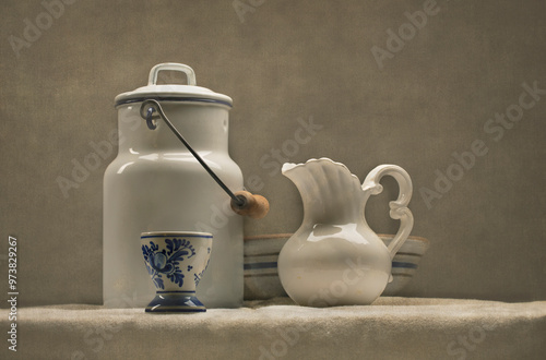 Antique milk can, milk pitcher and bowl arranged on a table