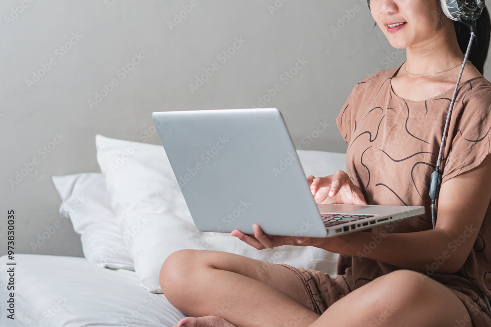 Naklejka premium Young Woman Working on Laptop in Cozy Bedroom
