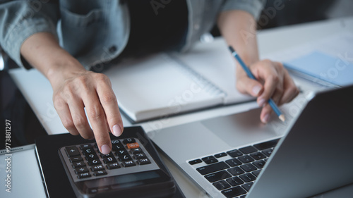 Foto Close up business woman hand using calculator to calculate home finance, accounting with laptop computer on table, budget management, monthly expenses