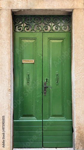 old wooden green door with ornate iron on top against stone frame photo