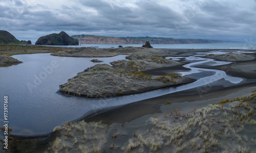 Swampland, tussock grass and sandunes with river flowing into the ocean at the Manukau Heads. Whatipu, Auckland, New Zealand. photo