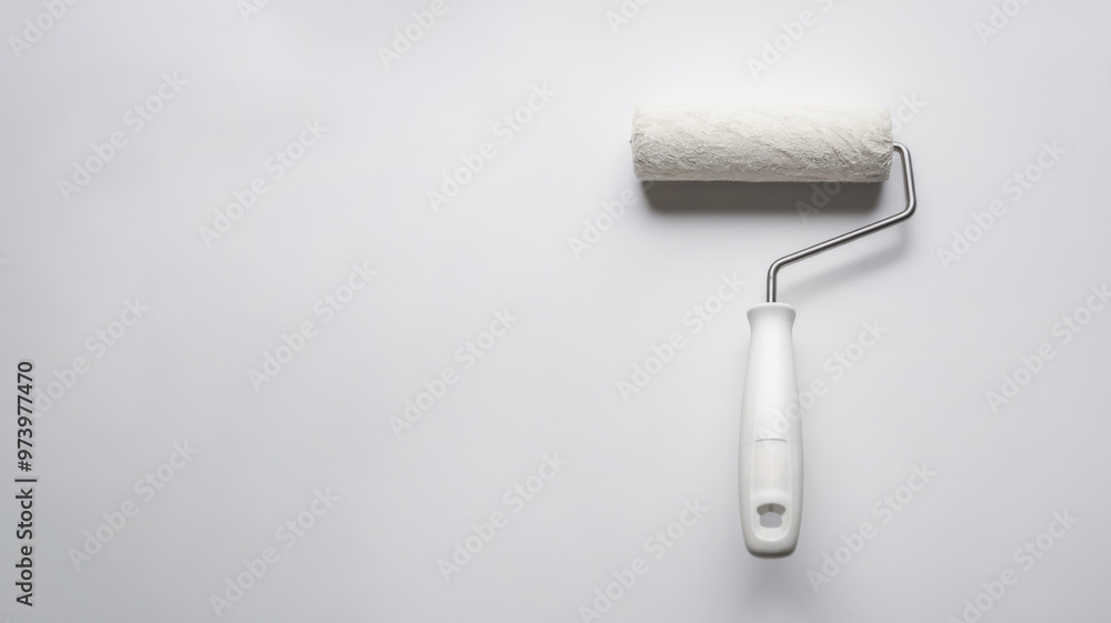 Obraz premium Paint roller on a white background. Tool for painting and home renovation. Minimalist style. Concept of DIY and home improvement projects.