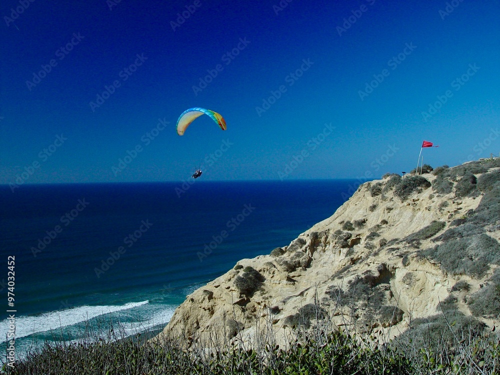 Paraglider soaring over Torrey Pines cliffs with the ocean below in California. Paraglider soaring over Torrey Pines cliffs with the ocean below in California.