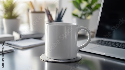 A simple white coffee mug on a coaster, placed on a sleek office desk with a laptop, plants, and stationery in the background.