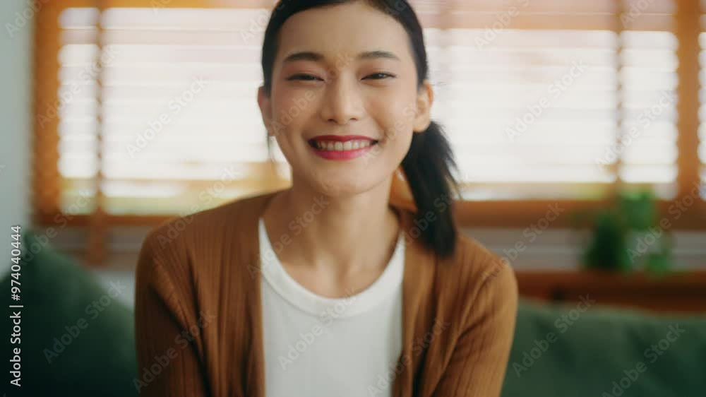 Happy young Asian woman relax on comfortable couch at home texting messaging on smartphone, smiling girl use cellphone, chatting online message, shopping online from home. Looking at camera Happy young Asian woman relax on comfortable couch at home texting messaging on smartphone, smiling girl use cellphone, chatting online message, shopping online from home. Looking at camera