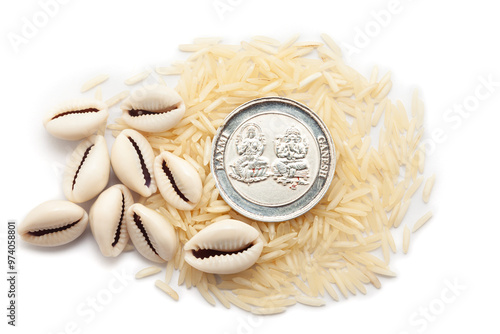 Top view of Cowries (Cypraea chinensis) and a silver coin placed over a pile of rice, isolated on a white background. photo