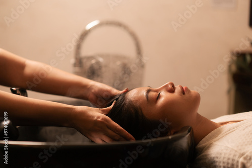 Asian woman customer feeling relax while hairdresser massaging head in procedure of steaming water steam. A female customer get service hair care at luxury beauty salon.