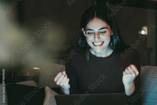 Happy woman celebrating in front of her laptop, exulting with joy after achieving a significant milestone, such as winning a sports bet, acing an exam, or finding a new job or online date, photo