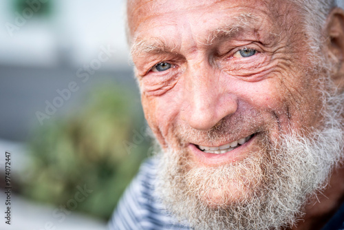 Obraz na plátně Portrait of an elderly man with blue eyes smiling sadly alone in a park