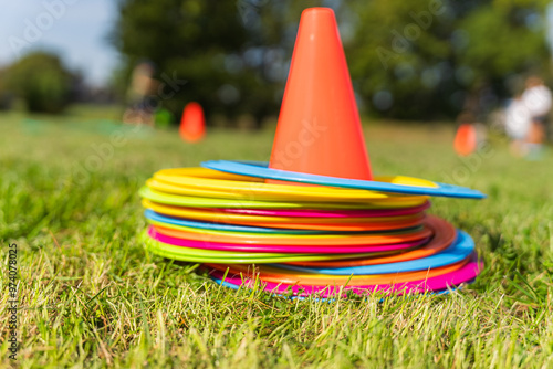 Background with a red cone and colorful game circles in the grass. Children's game concept