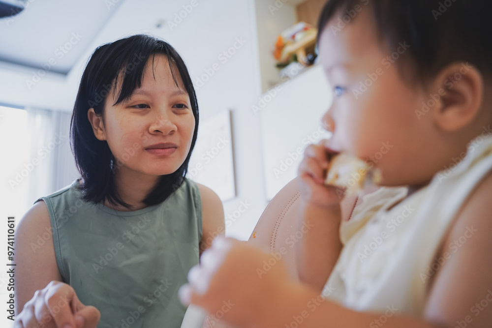 Asian woman coaxing her child to eat lunch
