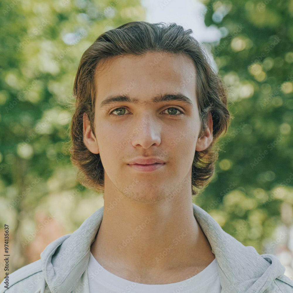 Closeup portrait of happy handsome young man at the park in summer. Cheerful teenager looks to the camera, outdoor portrait. Handsome face of a male model with brown hair at the city. One person Closeup portrait of happy handsome young man at the park in summer. Cheerful teenager looks to the camera, outdoor portrait. Handsome face of a male model with brown hair at the city. One person