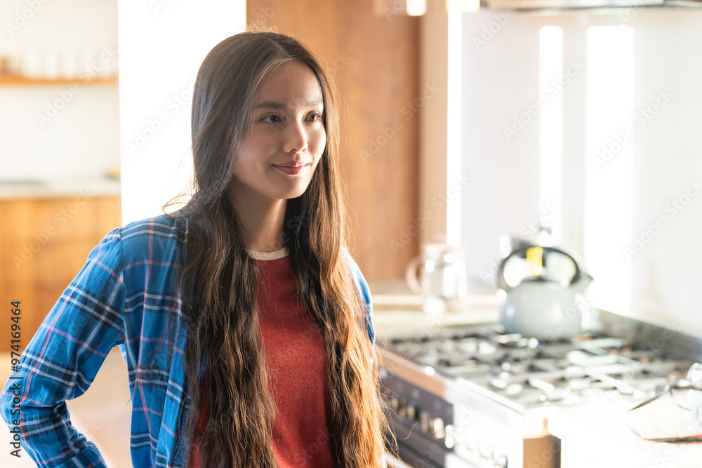 At home, Smiling young asian woman standing in kitchen near stove, wearing casual plaid shirt At home, Smiling young asian woman standing in kitchen near stove, wearing casual plaid shirt
