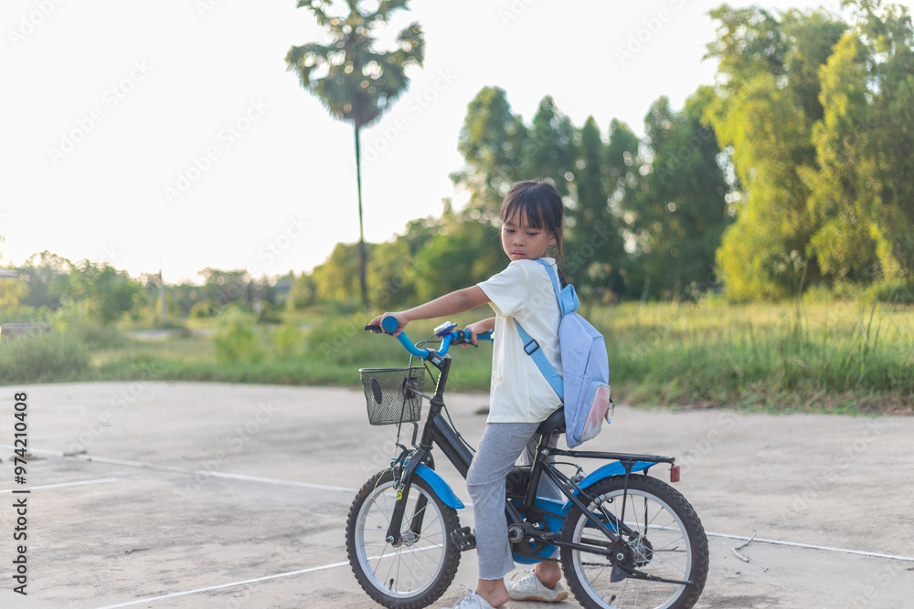 Fototapeta premium A young girl is riding a bicycle with a basket on the front.