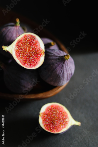 Close up of fresh ripe fig fruits in a wooden bowl on dark grey table 