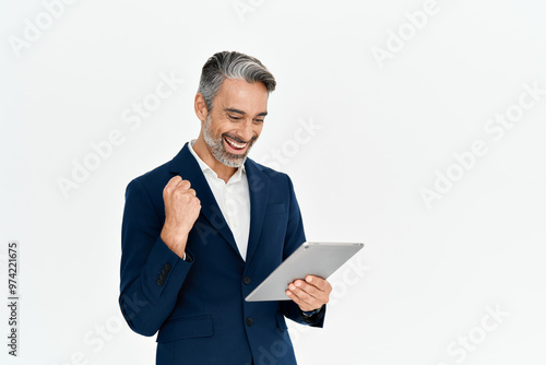 Happy middle aged business man entrepreneur, excited professional businessman winner wearing suit holding digital tablet celebrating online win, business success standing isolated on white background. photo