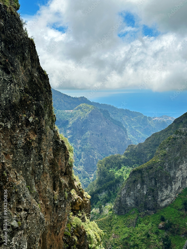 Fototapeta premium Hiking mountain trail among rocks and plants with a view of the clouds and gorge