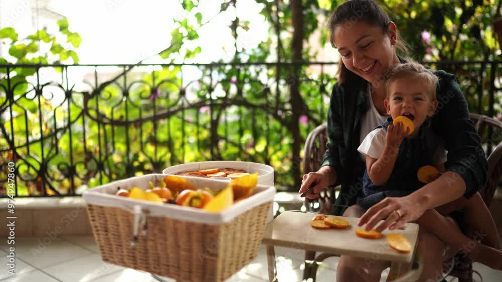 Little girl eats pieces of persimmon while sitting with her mother cutting persimmons. High quality 4k footage Little girl eats pieces of persimmon while sitting with her mother cutting persimmons. High quality 4k footage