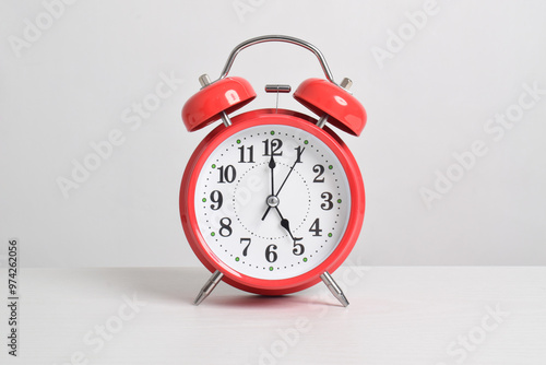 Red alarm clock set at five o'clock on table isolated on white background close-up with clipping path