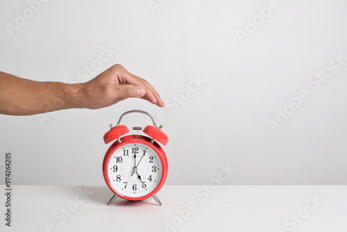 Man holding red alarm clock in hand on table isolated on white background. Close-up with clipping path