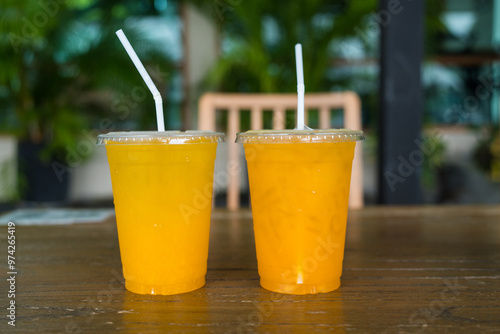 Iced of passion fruit and iced orange juice in a plastic cup on wood table