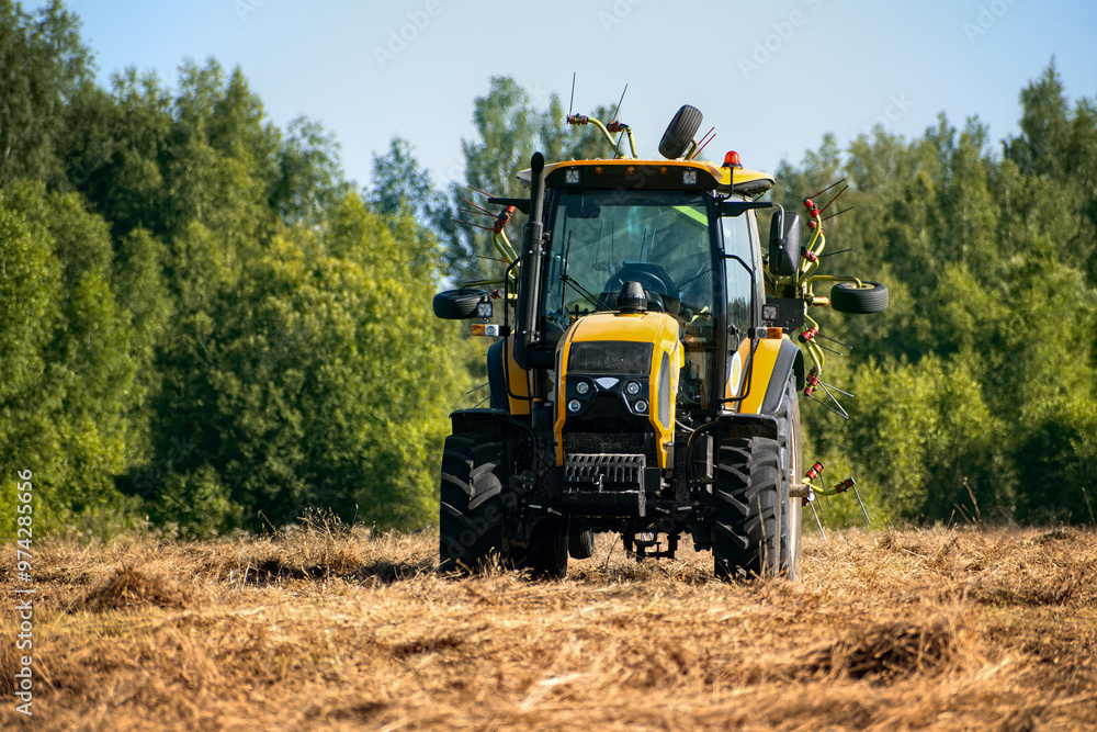 Modern agricultural tractor harvesting grass in the field Modern agricultural tractor harvesting grass in the field