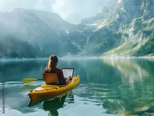 Woman Kayaking on Serene Mountain Lake with Laptop