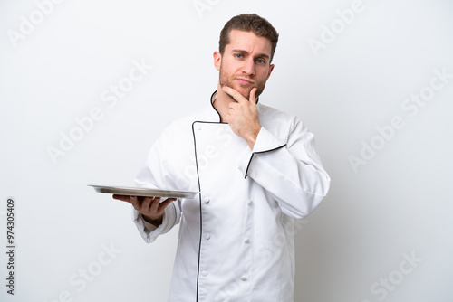 Young caucasian chef with tray isolated on white background thinking