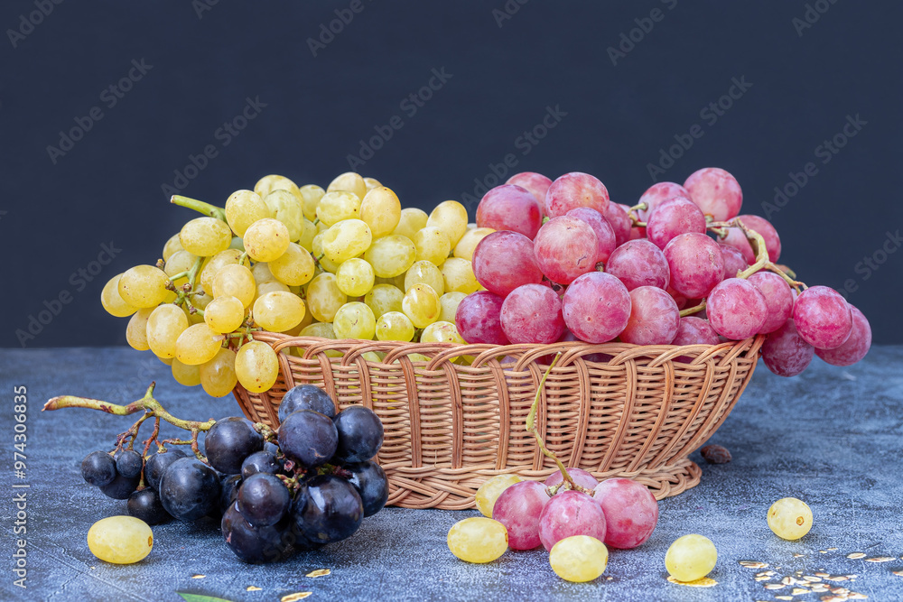 Yellow, black and red grapes in a wicker basket on a table.