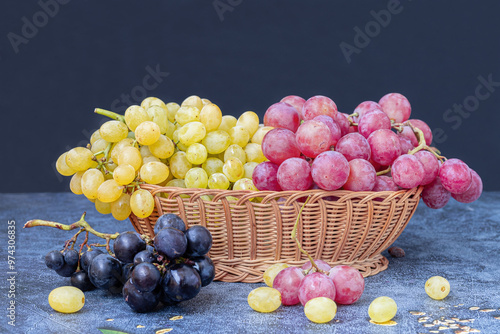 Obraz na płótnie Yellow, black and red grapes in a wicker basket on a table. w salonie
