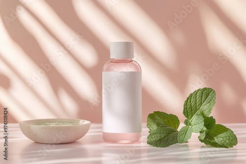 A minimalist scene featuring a pink liquid in a bottle, mint leaves, and a small dish.