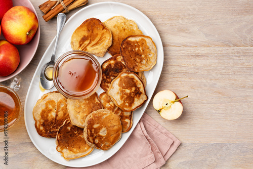 Homemade apple fritters with honey on a large white plate on a wooden table. Healthy tasty breakfast. Top view. Copy space