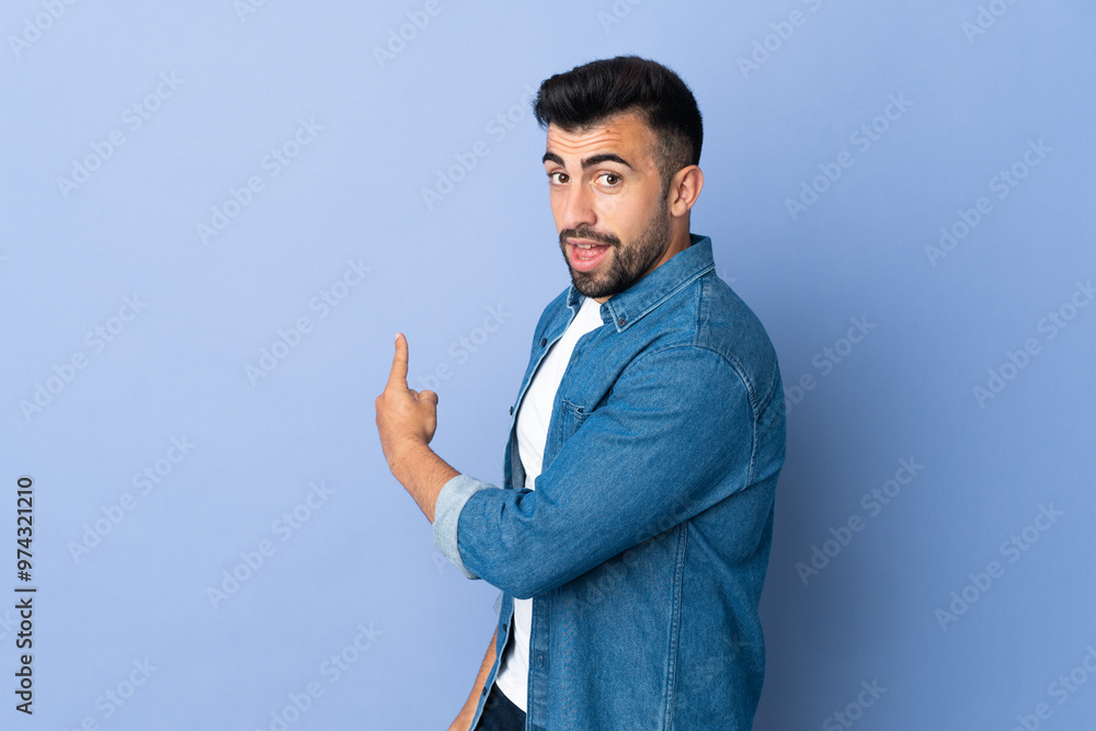 Caucasian man over isolated blue background pointing back Caucasian man over isolated blue background pointing back